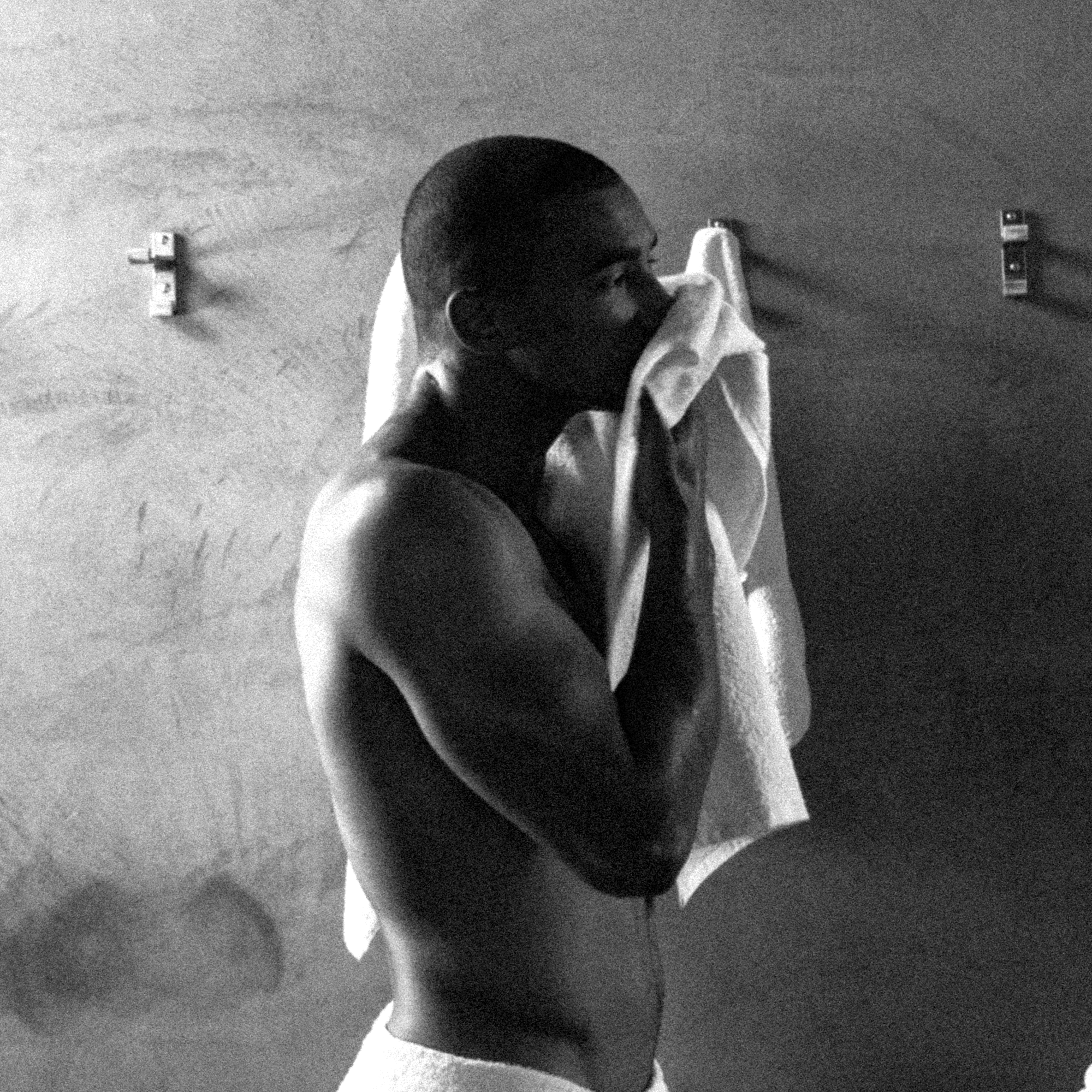 Man drying his face with a towel in a minimalist bathroom setting, highlighting personal care and wellness.