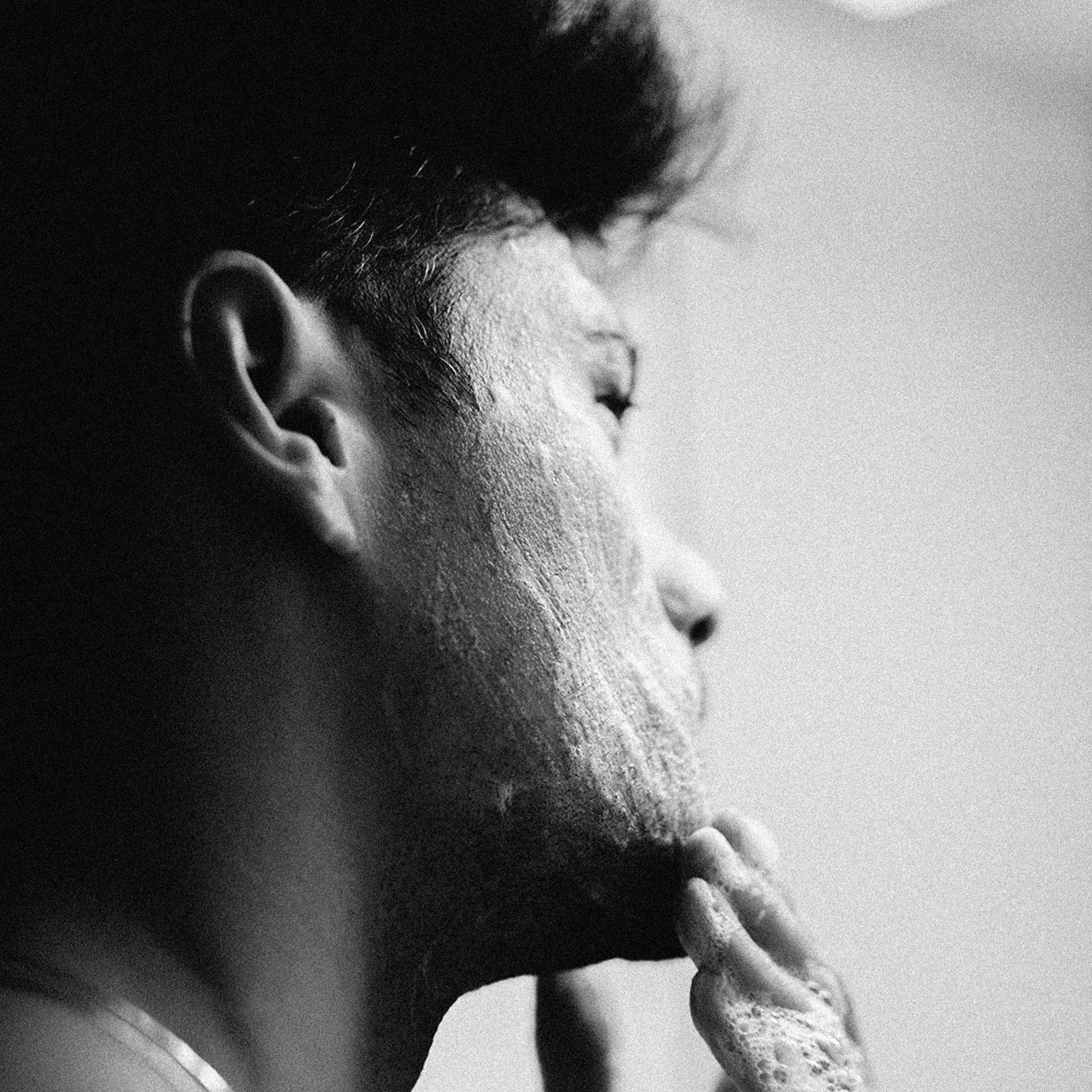 A man displaying a skincare routine, products by Reyal Performance.